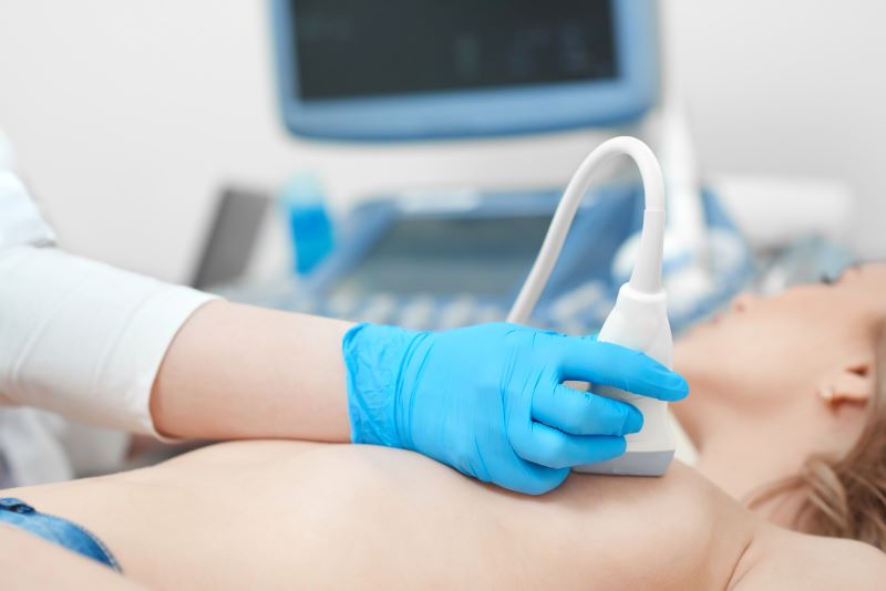 Woman receiving a breast ultrasound by a technologist.