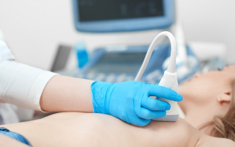 Woman receiving a breast ultrasound by a technologist.